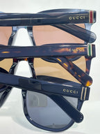 Gucci sunglasses with glossy dark frame and smoky lenses, side logo bar
