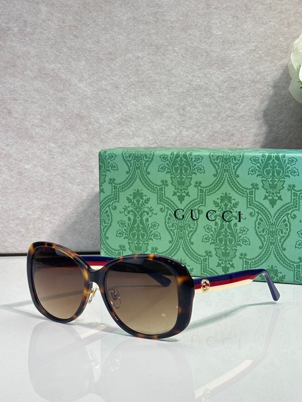 Gucci glasses with dark frames, tinted lenses, and gold logo detail at the temple arm.