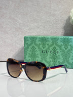 Gucci glasses with dark frames, tinted lenses, and gold logo detail at the temple arm.