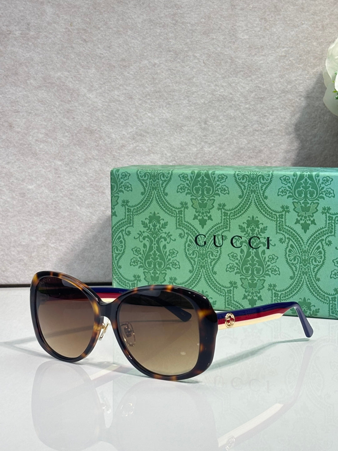 Gucci glasses with dark frames, tinted lenses, and gold logo detail at the temple arm.