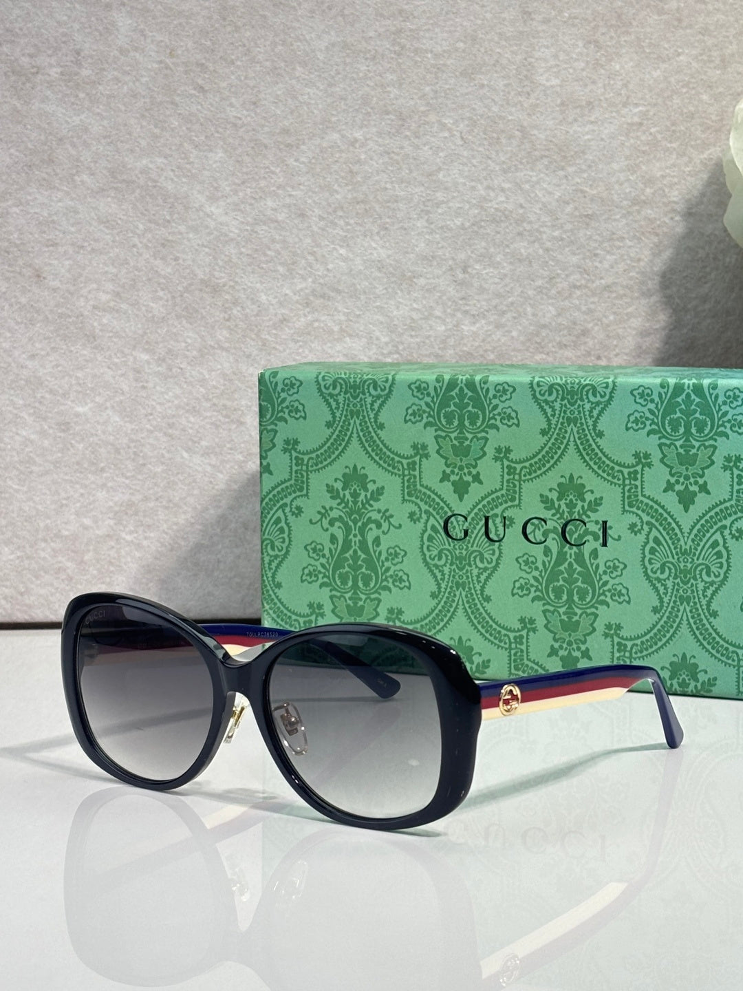 Gucci glasses with dark oversized frames, tinted lenses, and gold logo on the temple tip.