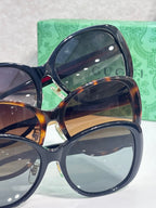 Gucci glasses with rounder dark frames and layered colored temple stripes, tinted lenses in view.
