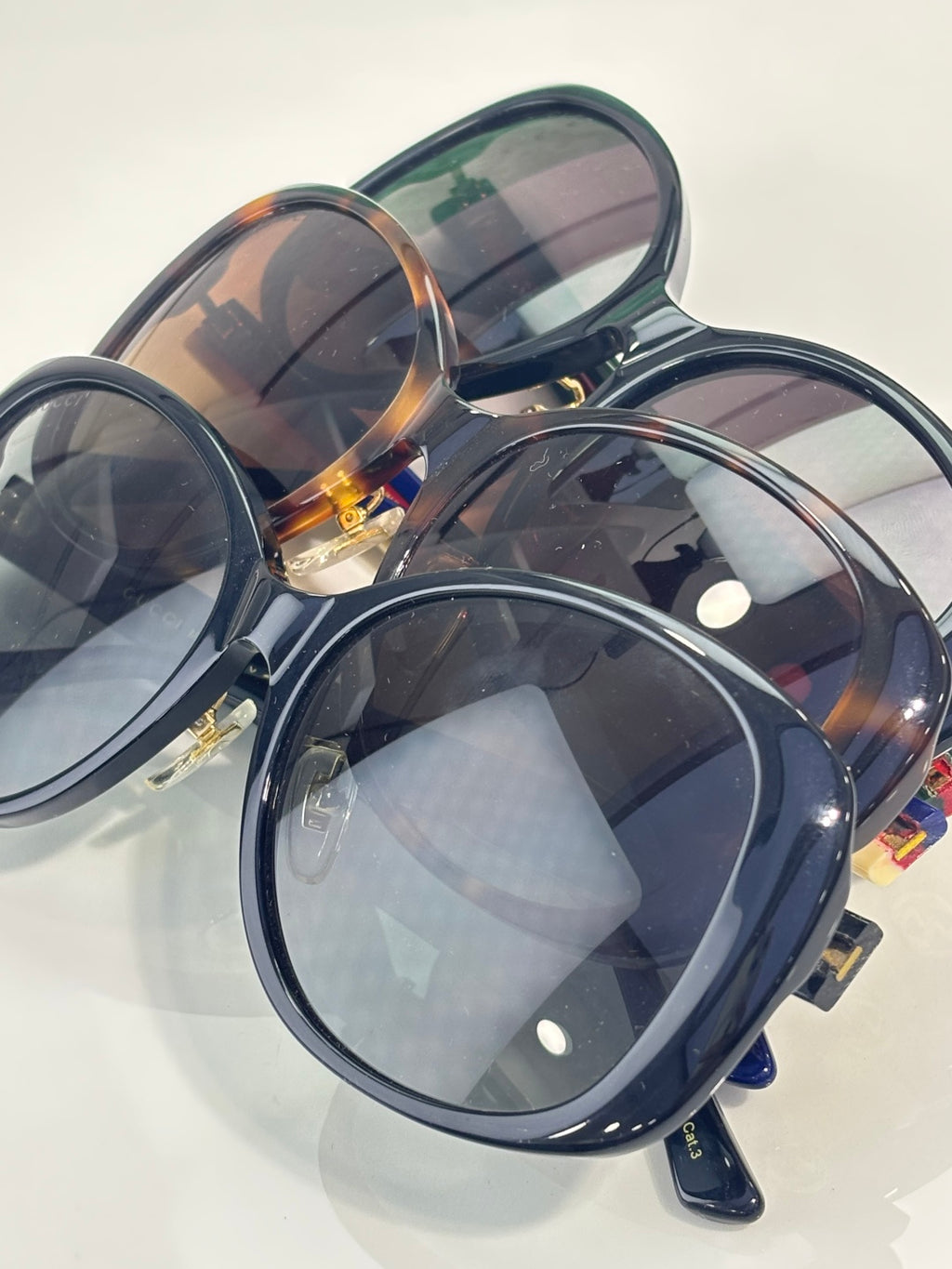 Gucci glasses set with oversized round dark frames, tinted lenses, and gold logo hinge details.