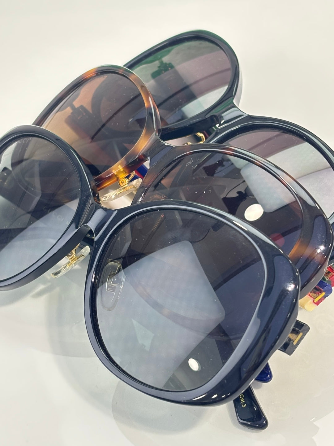 Gucci glasses set with oversized round dark frames, tinted lenses, and gold logo hinge details.