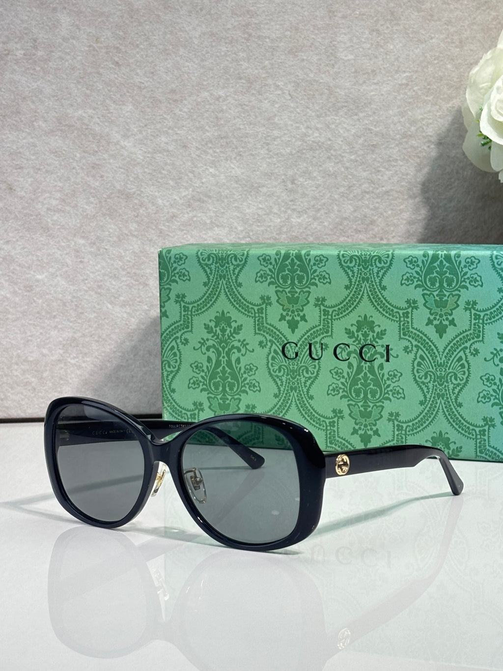 Gucci glasses with dark oversized frames and tinted lenses, featuring gold logo on the temple.