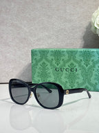 Gucci glasses with dark oversized frames and tinted lenses, featuring gold logo on the temple.