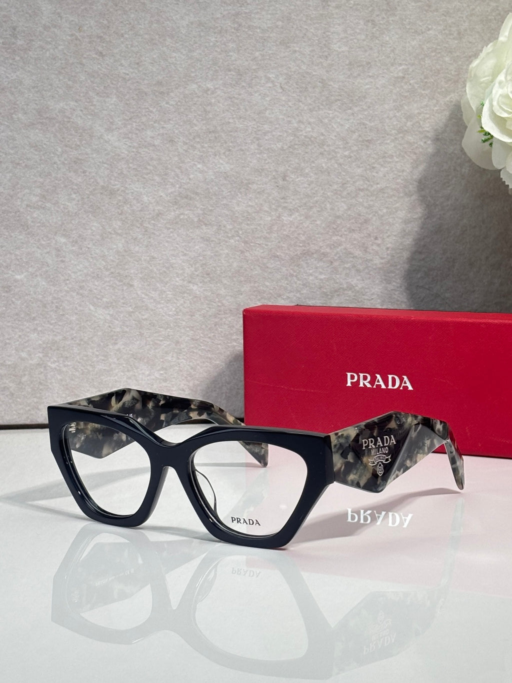 Black square eyeglasses with dark tortoiseshell arms and clear lenses, Prada logo