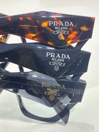 Dark patterned eyeglasses with clear lenses and Prada Milano logo on temple