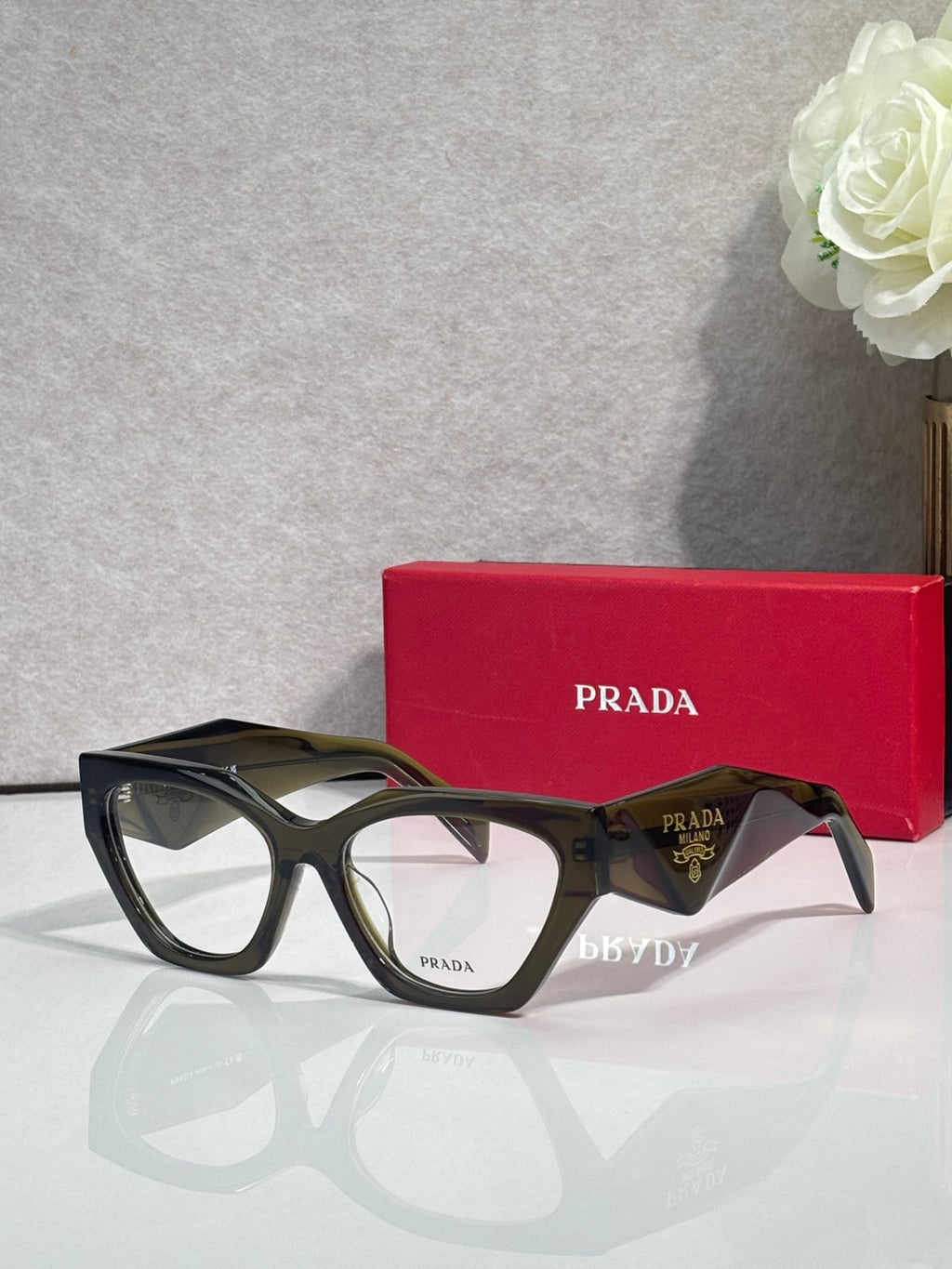Black eyeglasses with tortoiseshell arms and clear lenses, Prada logo on temple