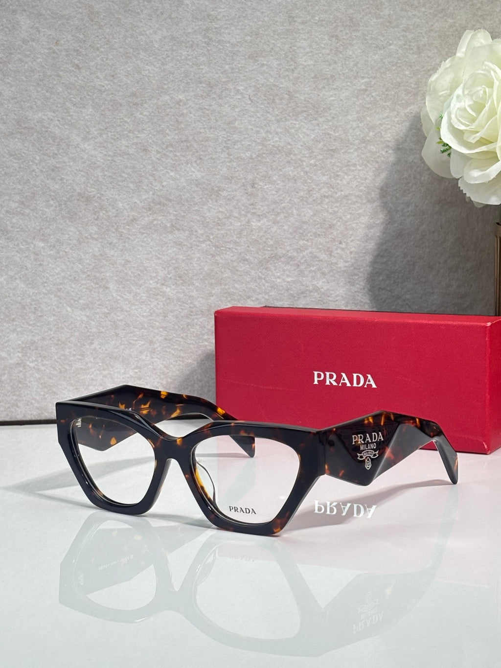 Dark tortoiseshell eyeglasses with black centers and clear lenses, Prada logo