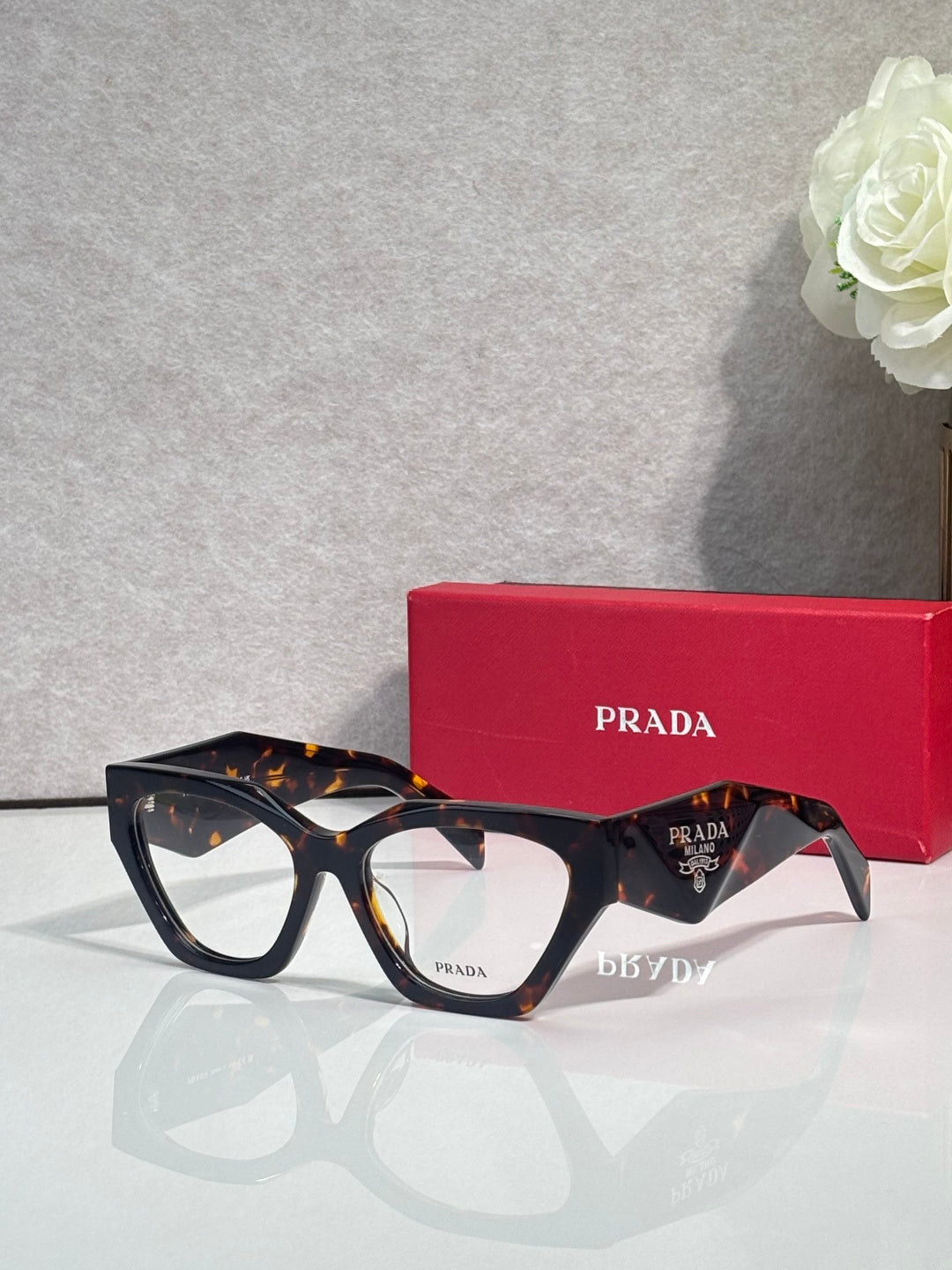 Dark tortoiseshell eyeglasses with black centers and clear lenses, Prada logo