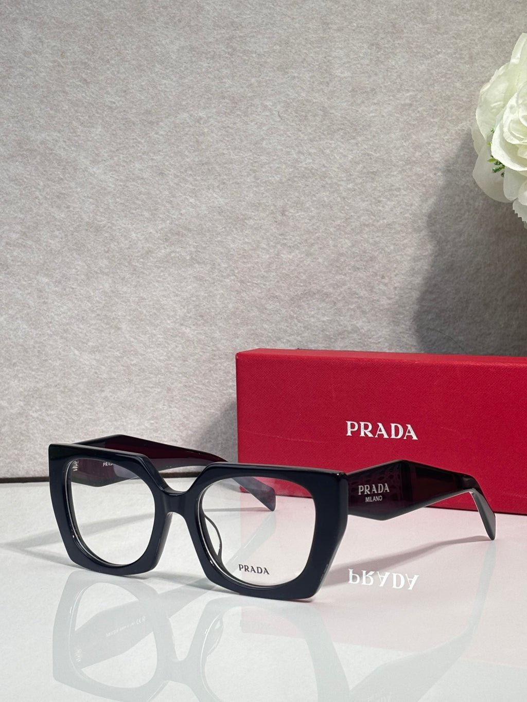 Square tortoise eyeglasses with black temples and Prada logo on the lens