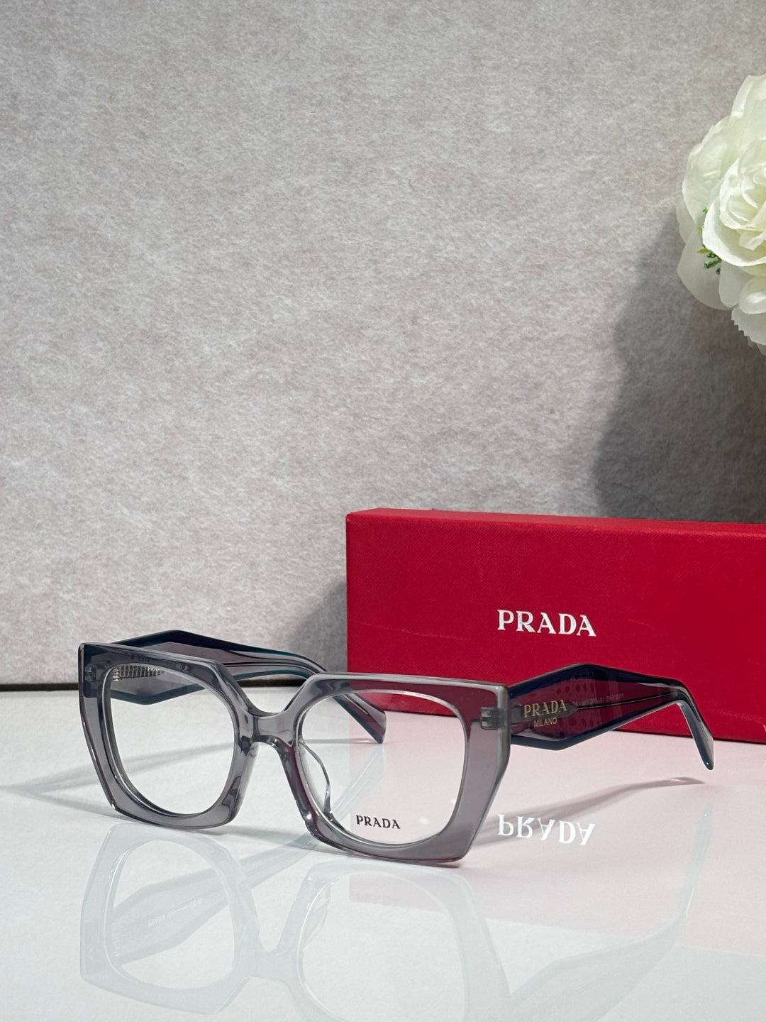 Rectangular dark metal eyeglasses with clear lenses and Prada logo on temple