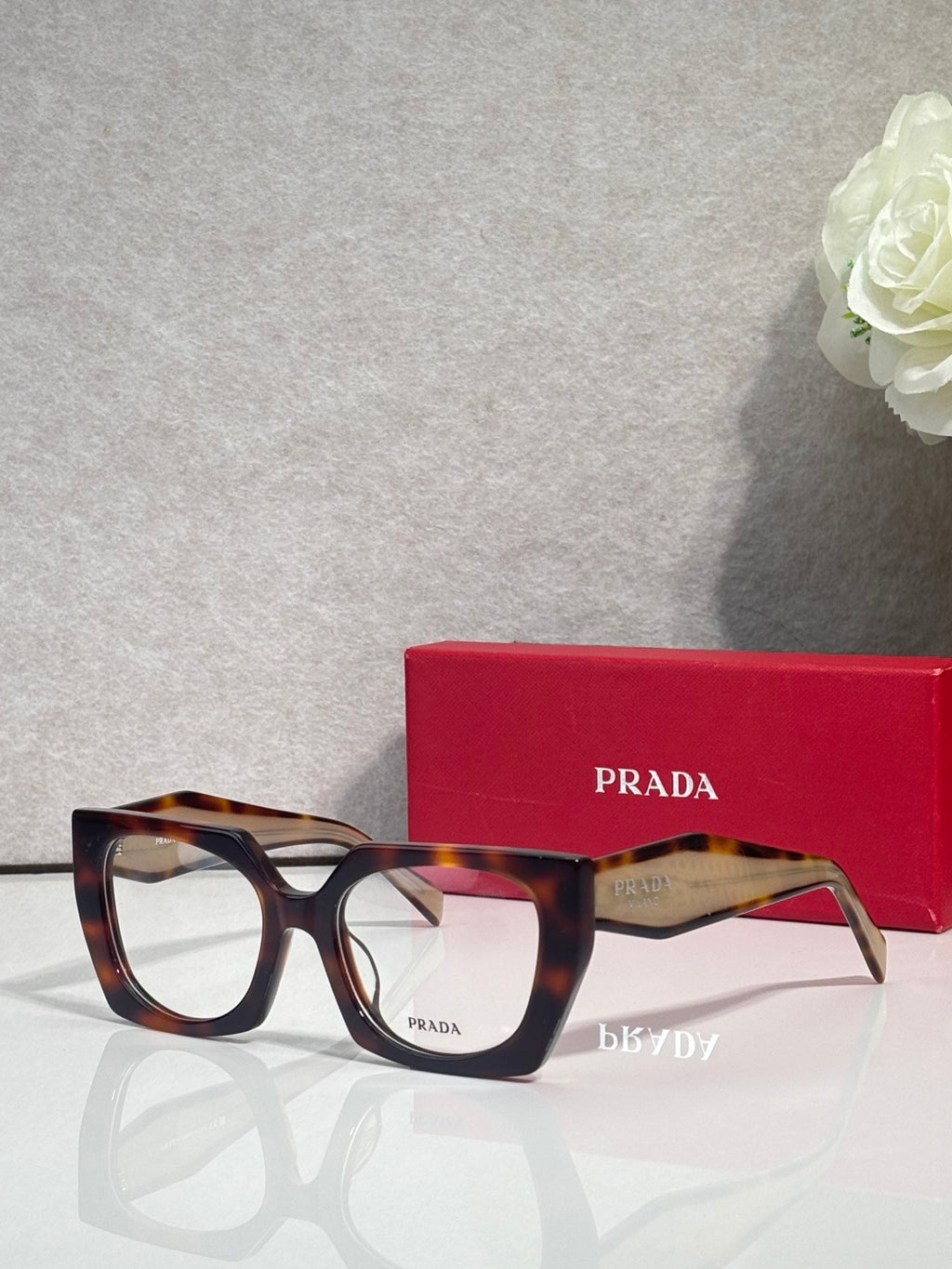 Square tortoise eyeglasses with clear bridge and Prada logo on the temple