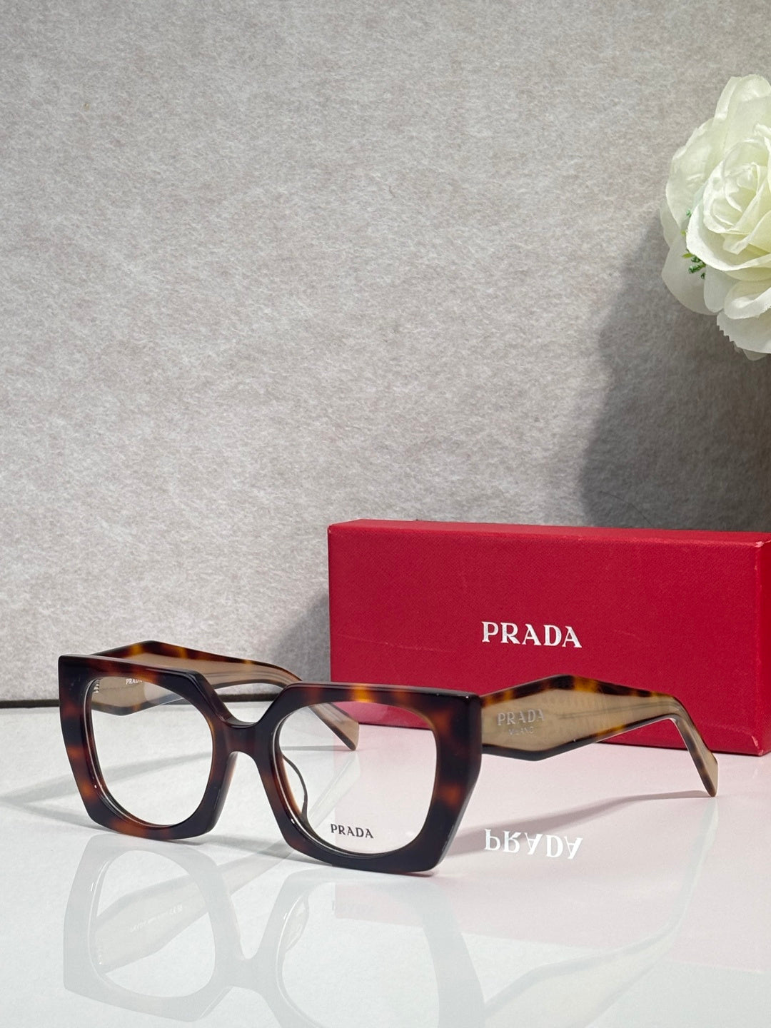 Square tortoise eyeglasses with clear bridge and Prada logo on the temple