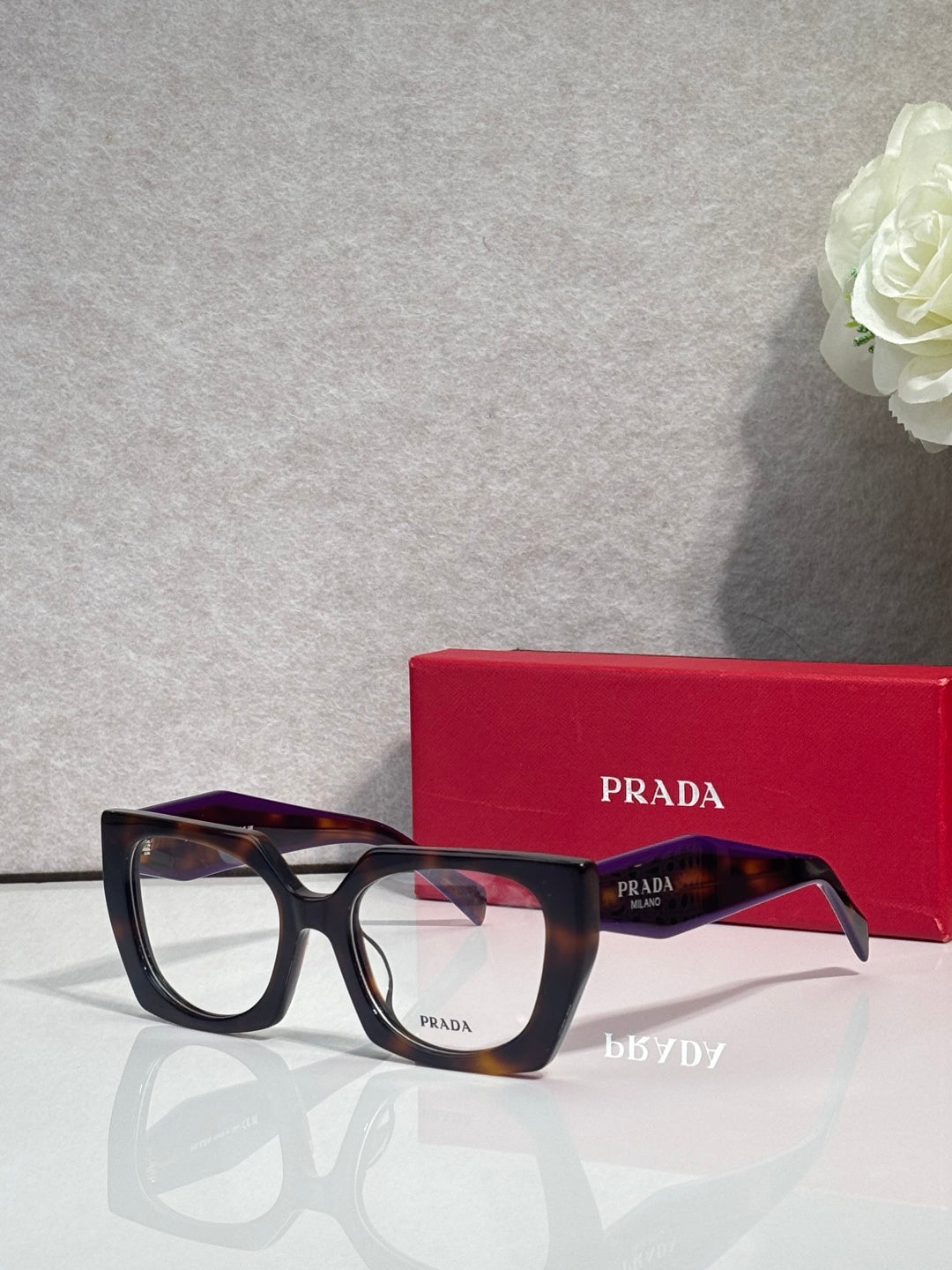 Square tortoise acetate eyeglasses with black frame accents and visible Prada logo