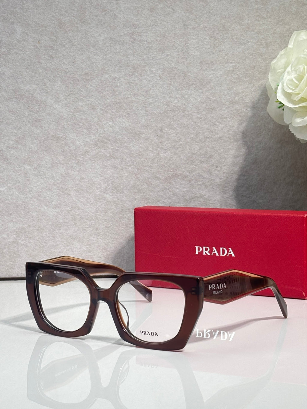 Square tortoise acetate eyeglasses with dark lenses and Prada logo on front