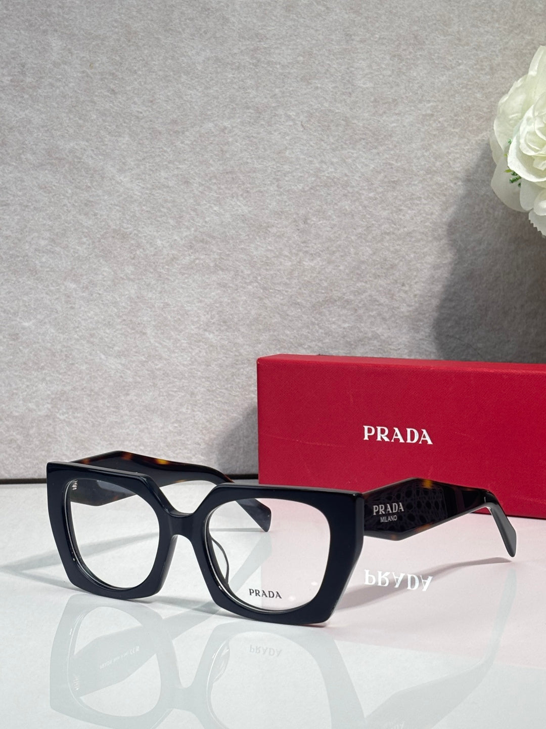 Square black eyeglasses with clear lenses and Prada logo on the temple