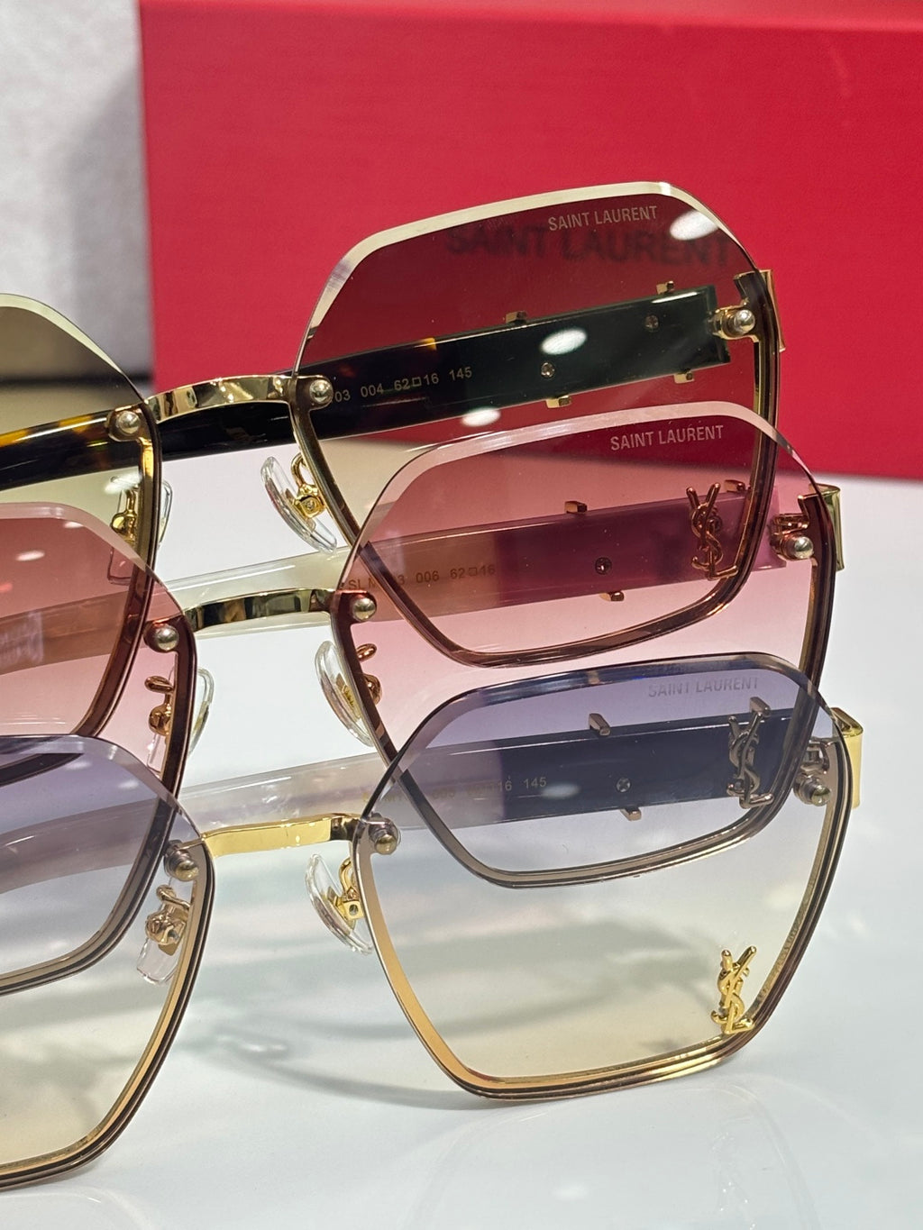 YSL glasses close-up: stacked tinted lenses with gold frame and logo accents