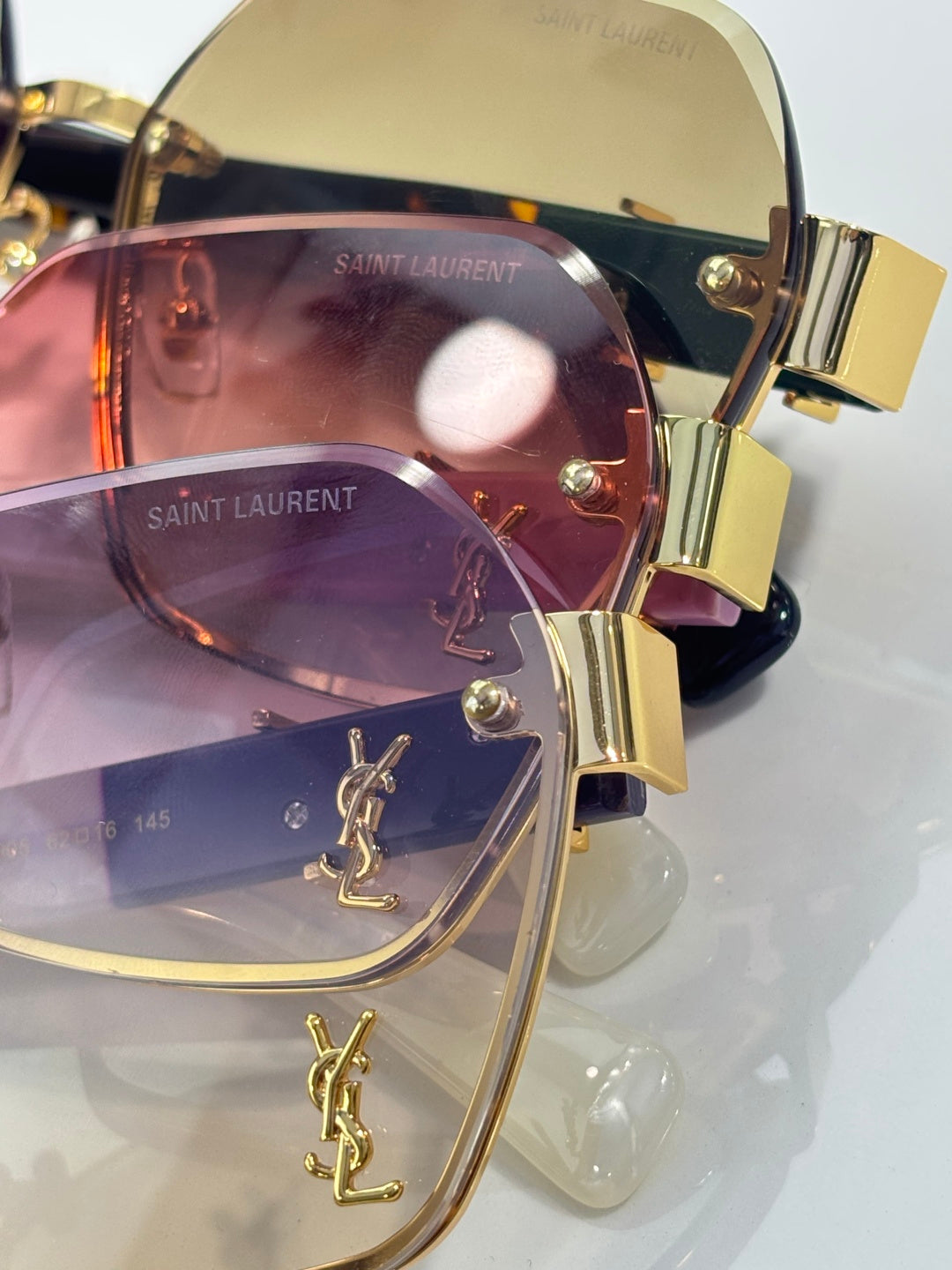 YSL glasses close-up: gold frame with YSL logo temples and tinted lenses