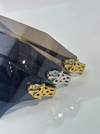 Cartier sunglasses close-up of gold temple detail with small green accents
