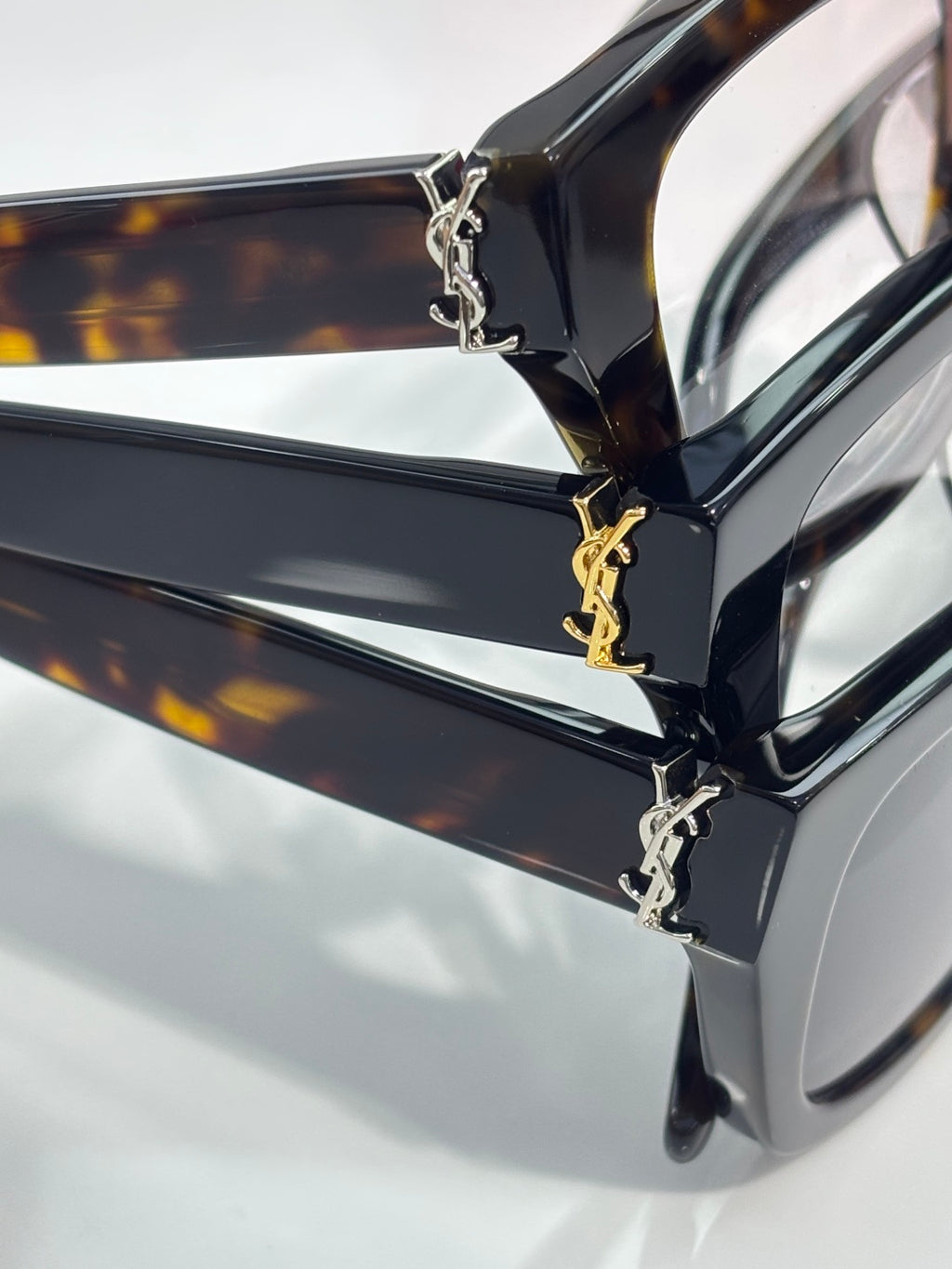 Close-up of tortoise acetate eyeglass frame with gold-tone chain hinge and temple