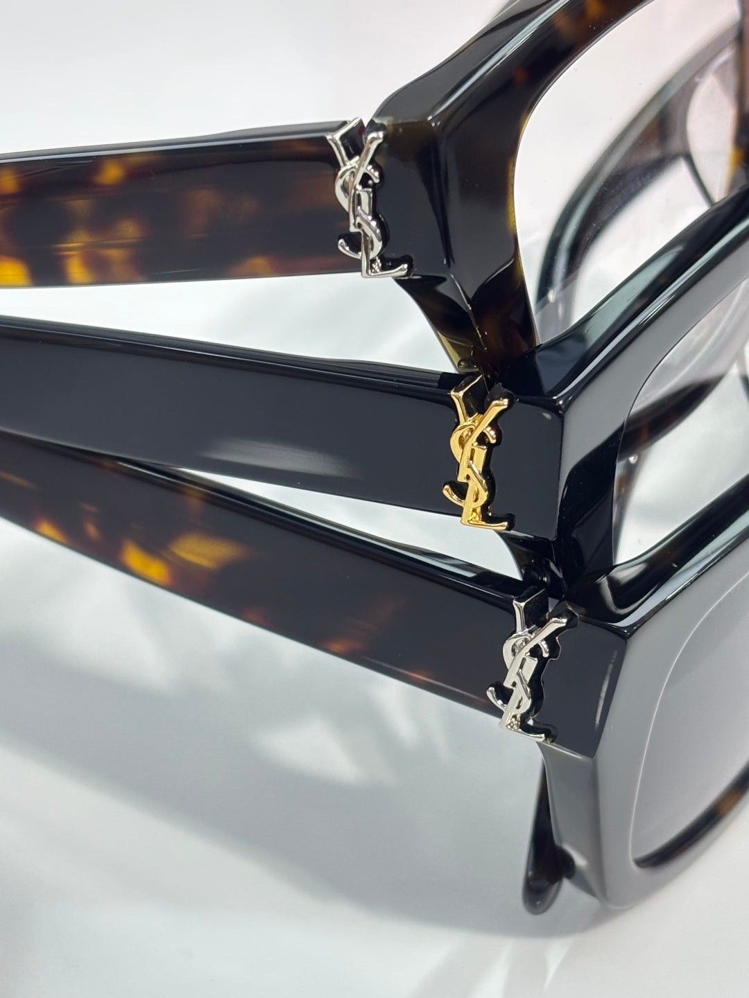 Close-up of tortoise acetate eyeglass frame with gold-tone chain hinge and temple
