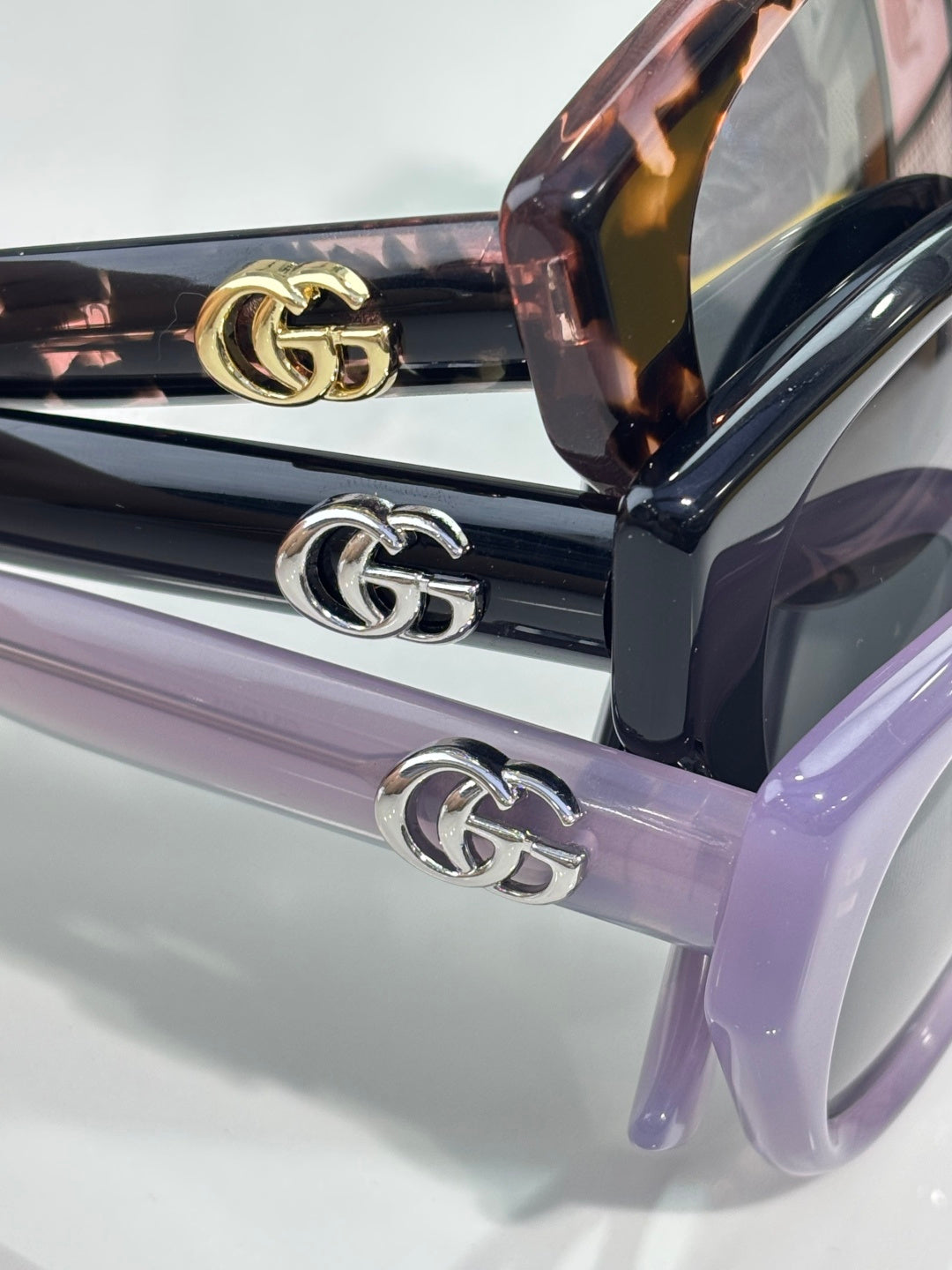 Gucci temple arms with GG logo, black and lavender sunglasses.