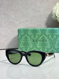 Gucci cat-eye sunglasses, black frame with green tinted lenses.