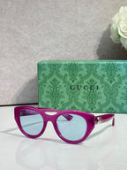 Gucci cat-eye sunglasses, magenta frame with light blue lenses.