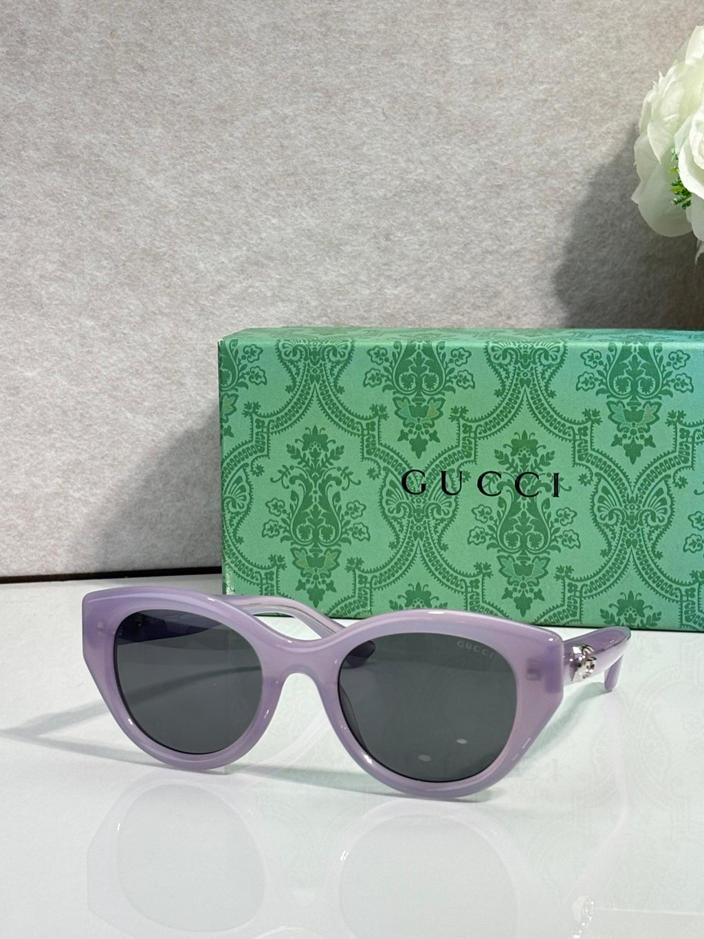 Gucci cat-eye sunglasses, light purple frame with dark lenses.