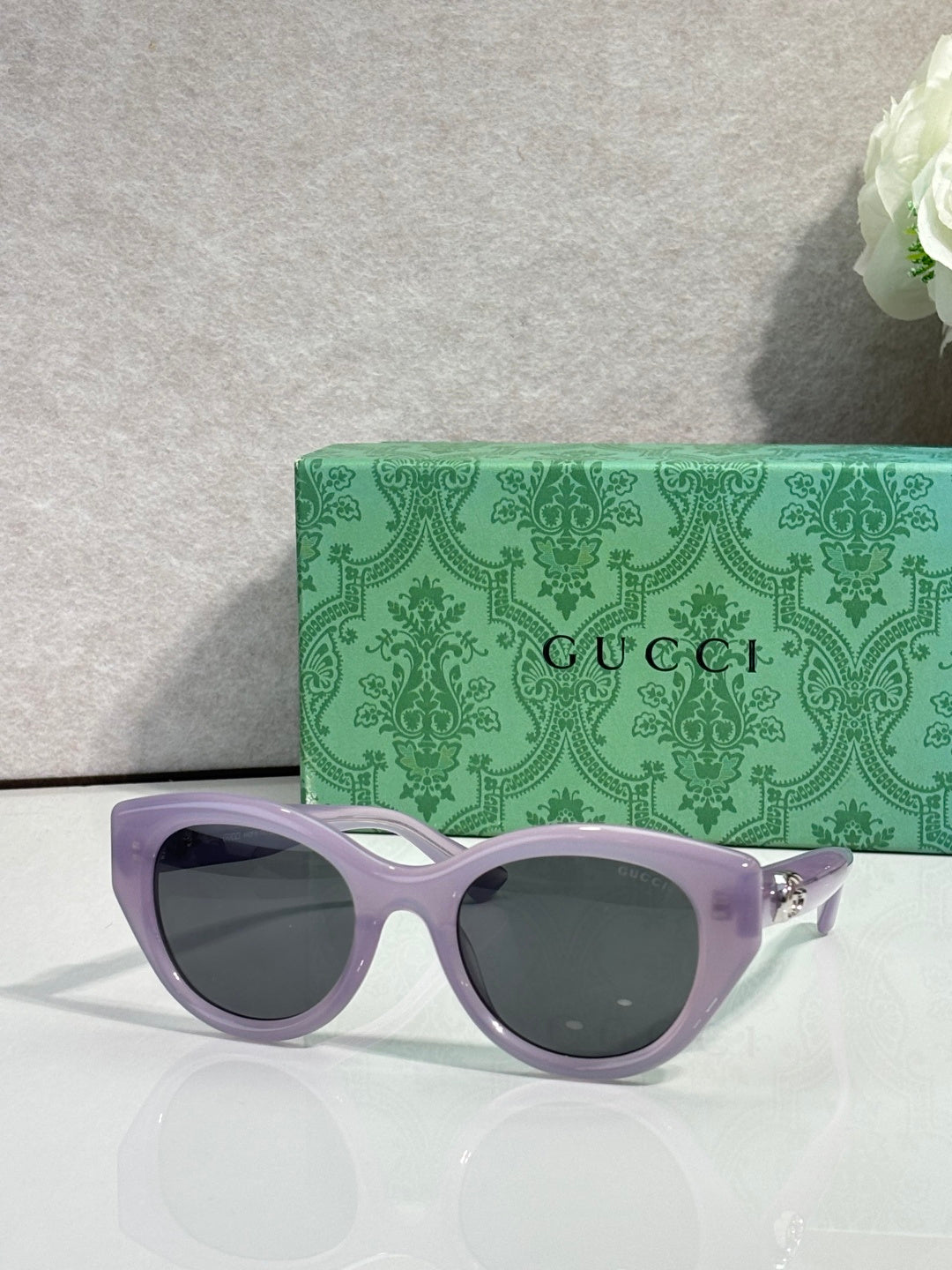 Gucci cat-eye sunglasses, light purple frame with dark lenses.