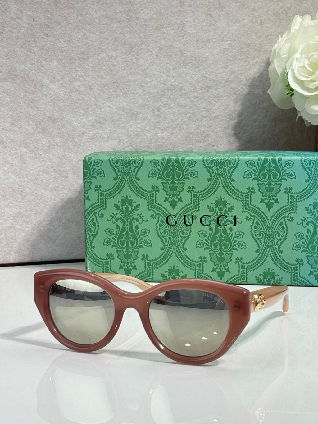 Gucci cat-eye glasses, brown frame with light lenses.