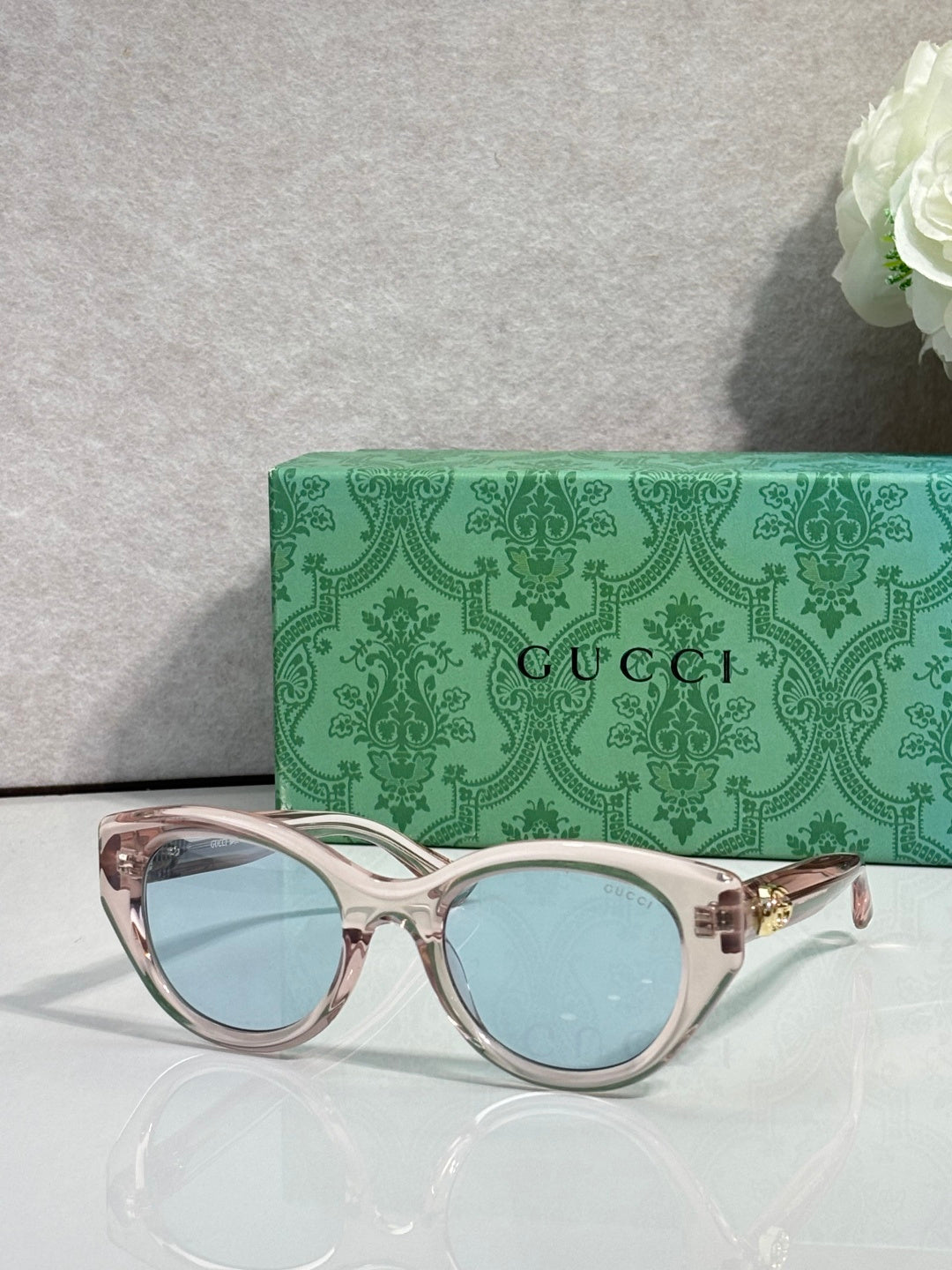 Gucci cat-eye glasses, rose-gold frame with light blue lenses.