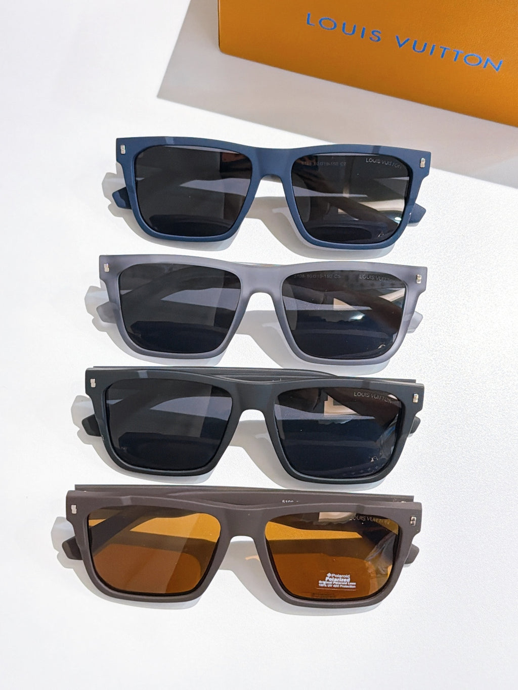 Louis Vuitton sunglasses set of four pairs, stacked; blue, gray, black, and amber lenses.