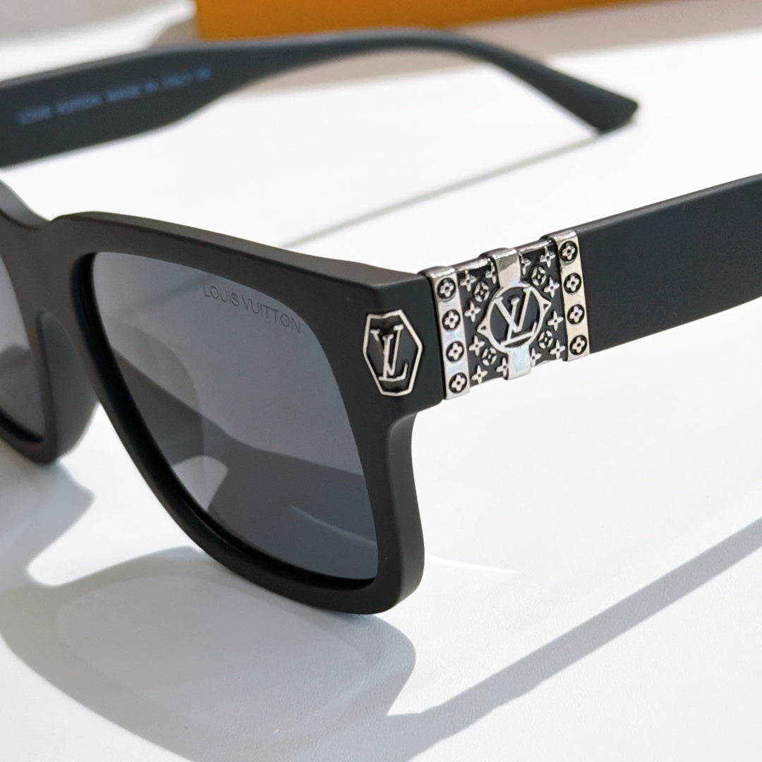 Louis Vuitton sunglasses close-up: patterned temple band with shield logo, black frame.