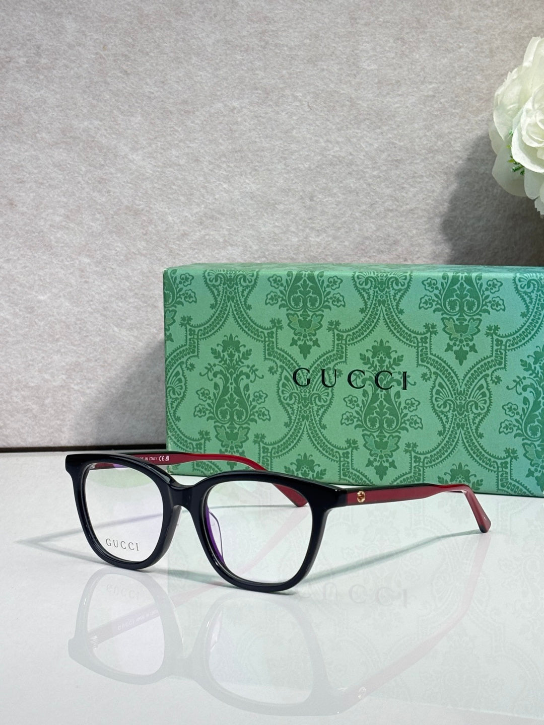 Gucci eyeglasses with black frames, clear lenses, and burgundy metal temple trim