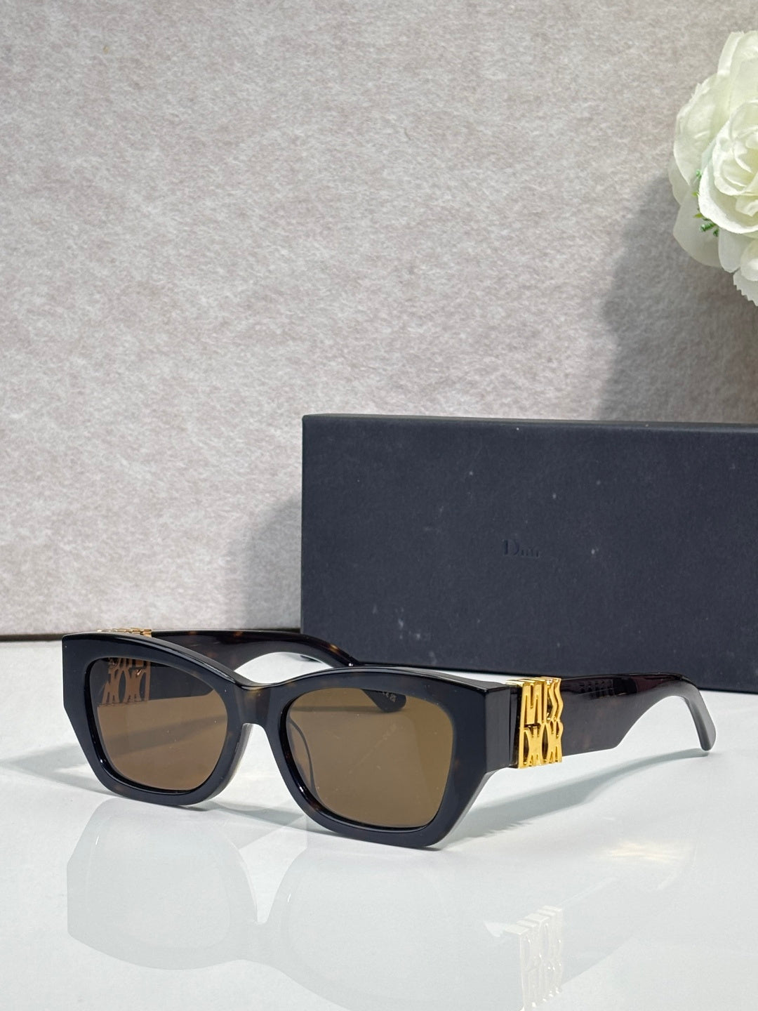 Sunglasses with black-blue frames, gold temple logo detail, square tinted lenses