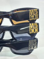 Sunglasses side view with dark frames, gold logo detail on temple, amber tinted lenses