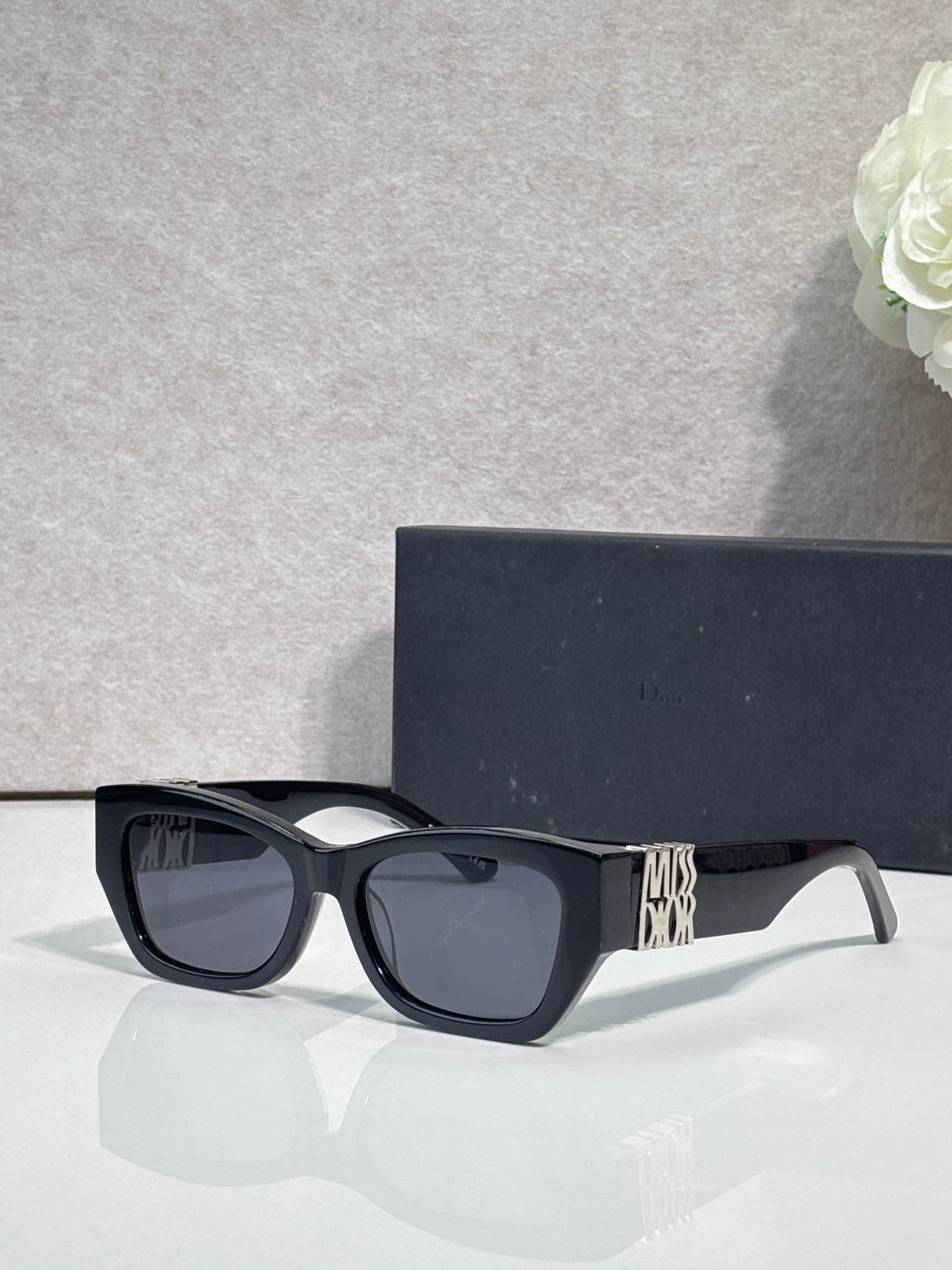 Sunglasses with dark navy frames and gold logo on side arm, tinted lenses