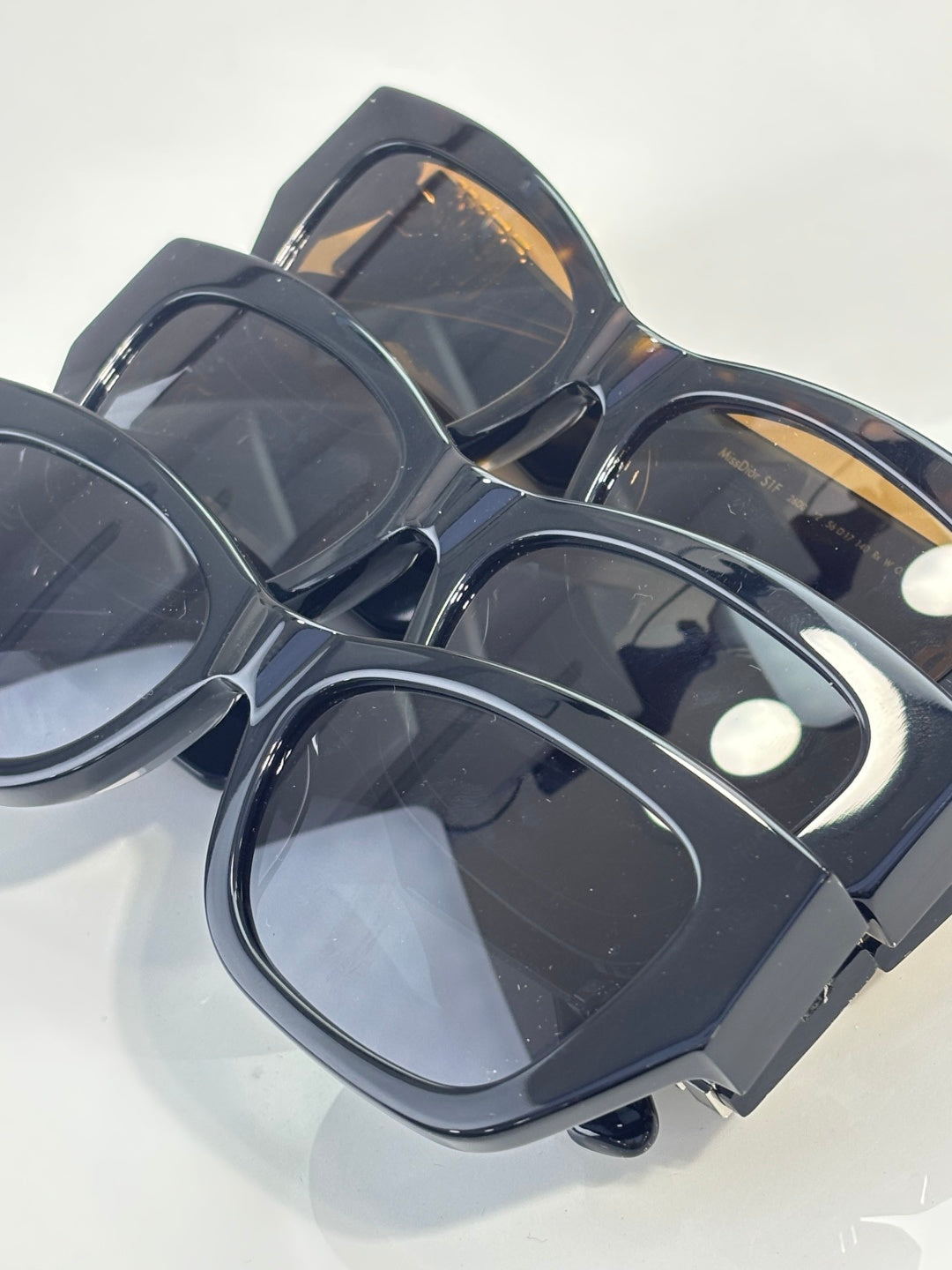 Sunglasses stacked view with dark frames and tinted lenses, gold temple accents