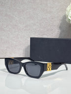 Sunglasses with dark navy cat-eye frames and gold geometric logo on temple, tinted lenses