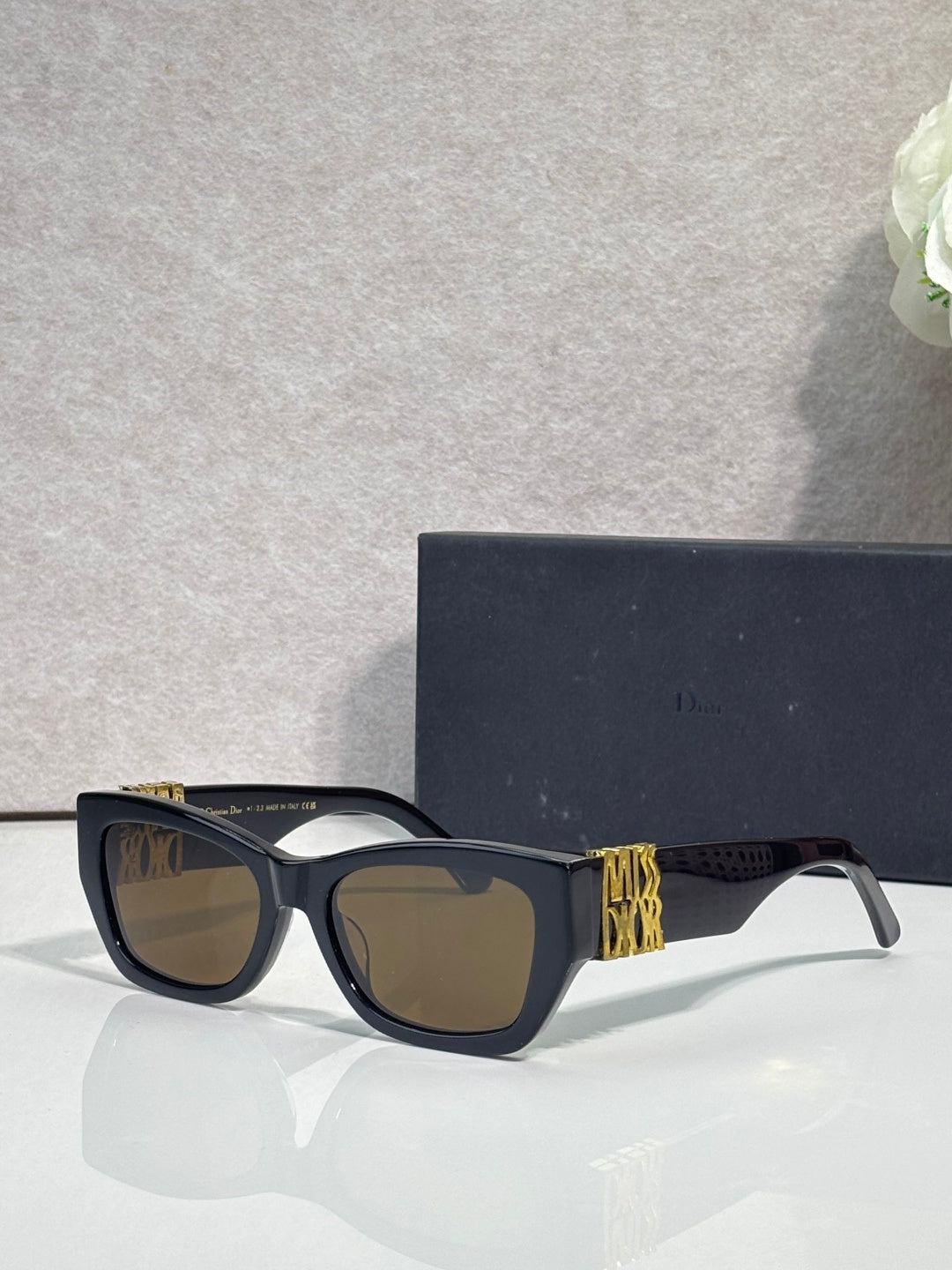 Dior sunglasses with dark navy square frames, gold logo side accents, tinted lenses