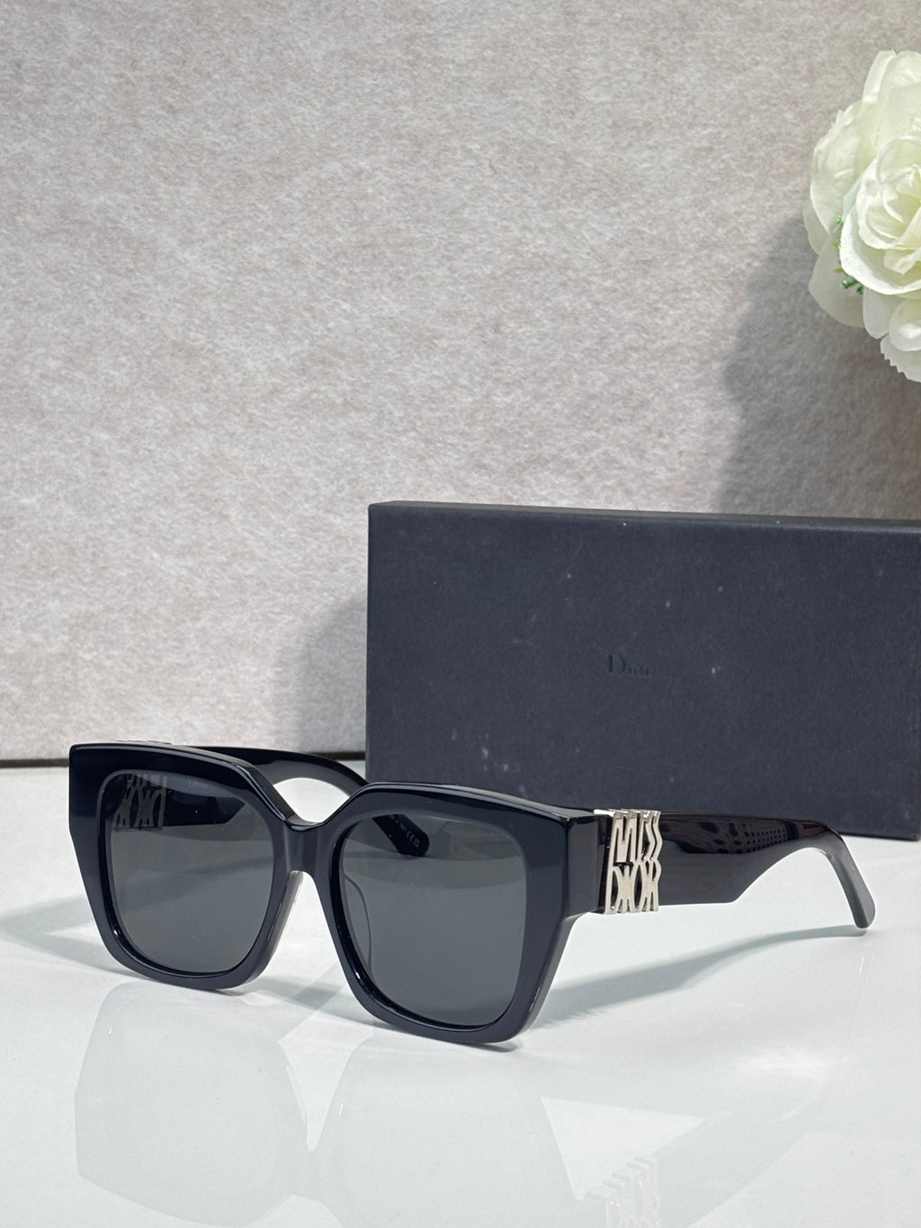 Dior sunglasses with black frames and dark gray lenses, gold logo on temple