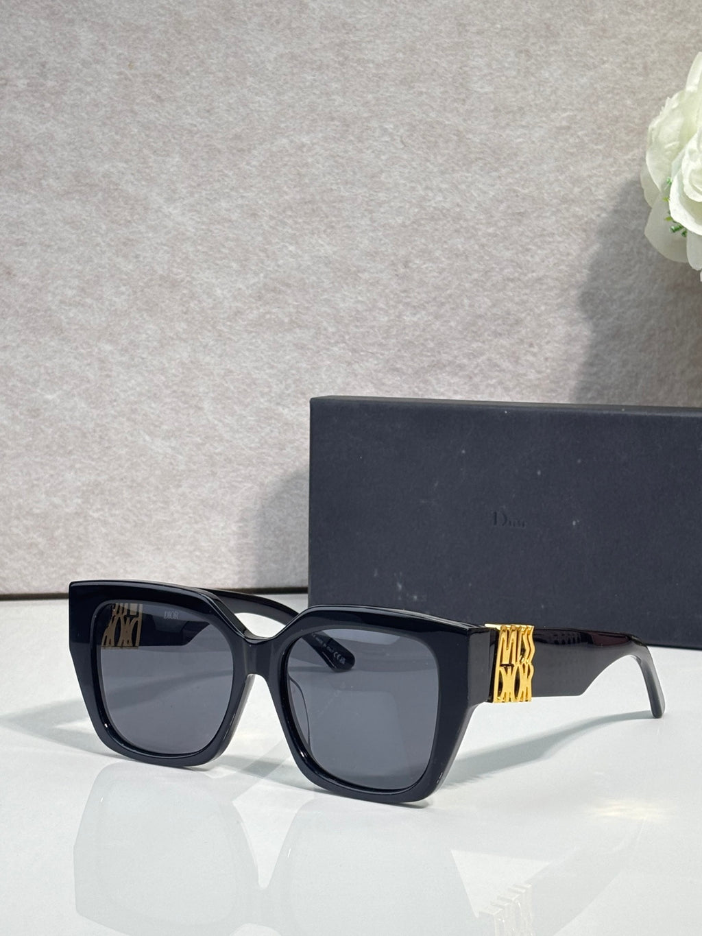 Dior sunglasses with dark frames and dark lenses, gold logo on temple