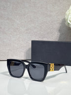 Dior sunglasses with dark frames and dark lenses, gold logo on temple