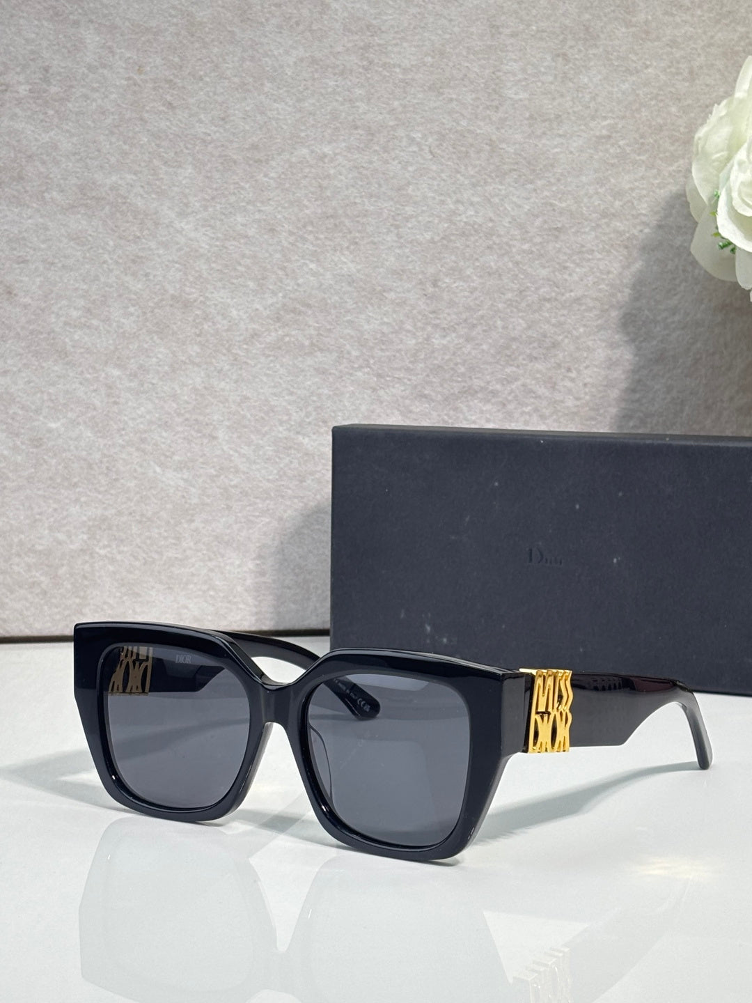 Dior sunglasses with dark frames and dark lenses, gold logo on temple
