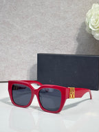 Dior sunglasses with red frames and dark lenses, gold logo on temple
