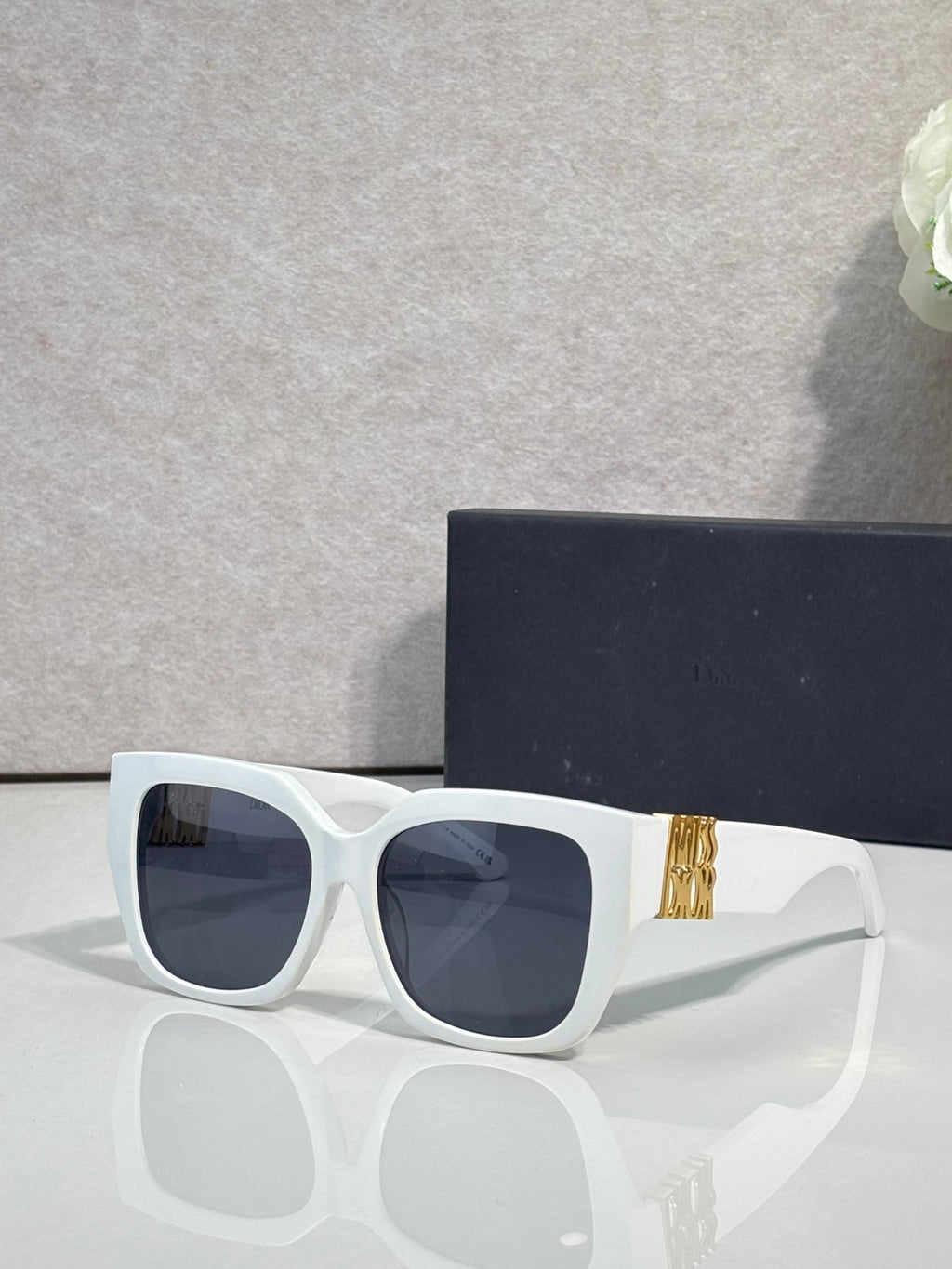 Dior sunglasses with white frames and dark lenses, gold logo detail on the temple