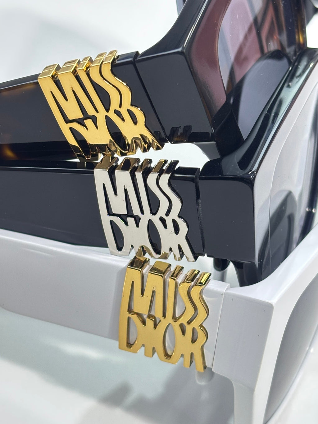 Dior sunglasses temple logo detail, glossy black with gold emblem lettering